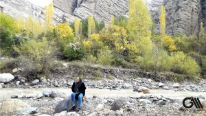 the photo shows a girl sitting on a rock in the season of Fall in Alamut Valley